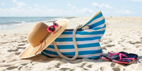 Hut und Tasche liegen an einem Strand im Sand