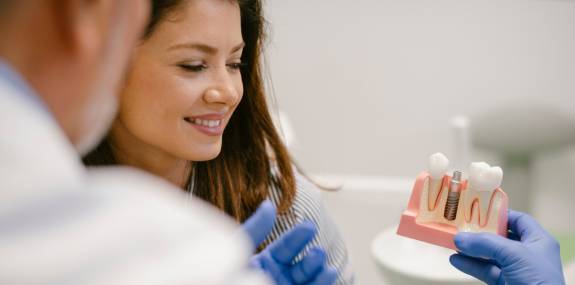Arzt erklärt Patienting Implantate anhand eines Models