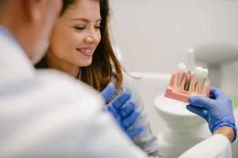 Arzt erklärt Patienting Implantate anhand eines Models